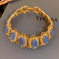 Dettaglio di bracciale vintage dorato con pietre blu ovali e incisioni floreali - Collana-Blu