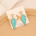 Bohemian bull head earrings with green resin and gold heart studs on white fabric - Green