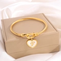 Golden heart charm bracelet featuring initial F on a stainless steel cable wire band - Letter F