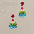 Detail von handgefertigten Weihnachtsbaum-Ohrringen mit roter Schleife und Kristallen - Mehrfarbiger Baum-Gepolsterter Clip / Clip-Ohrringe