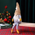 Handmade knitted Christmas gnome doll sitting on a wooden bench with festive decor - Brown Male