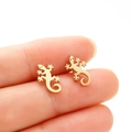 Polished gold stainless steel gecko stud earrings held to show compact size and fit - Gold