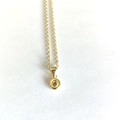 Detailed macro shot of a delicate gold chain necklace with a mini round letter O pendant - Letter O
