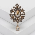 Macro shot of vintage gold brooch with champagne crystals on white geometric stand - Champagne