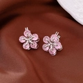 Detailed close-up of pink zircon flower earrings on luxurious dark brown silk fabric - Ear Buckle / Pink