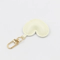 Detail view of a cream heart-shaped PU leather keychain with gold clasp and fine stitching - With Buckle / Beige