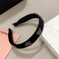 Macro detail of black velvet headband featuring heart-shaped sparkling rhinestone accents - Black