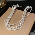 Detail einer mehrlagigen weißen Perlenkette mit goldenen Akzentperlen auf einem Display - Mehrlagige Gemischte Perlenkette mit Gold-Abstandshalterperlen
