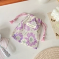 Close-up of floral drawstring storage bag made of cotton linen on a styled desk - Purple