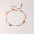 Detaillierte Nahaufnahme eines roségoldenen Herzarmbands mit kleinen Diamanten auf Beige - Roségold