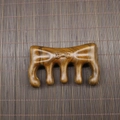Macro shot of sandalwood massage comb with 5 smooth round teeth on bamboo mat - Golden Sandalwood Bowknot Shape (9.5*5.8*1.8cm)