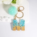 Blue resin letter M keychain with gold flakes, mint fur pompom and metal ring - Letter M
