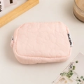 Detail of pink quilted makeup bag with flower texture and soft fabric on wooden table - Pink