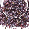Macro shot of 6x8mm teardrop glass beads in mixed colors spilling from a white bowl - Purple Series