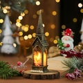 Close-up of bronze church-shaped Christmas lantern with LED candle on a wood base - Bronze-colored Old Man Pulling A Deer Cart