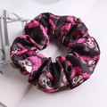 Detail of black fabric scrunchie with skull and pink flower print on white background - Pink Black