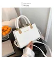 Macro shot of white lychee leather tote bag with unique woven handle and gold hardware - White