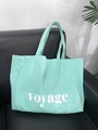 Detail of mint green canvas tote bag with Voyage lettering on a leather background - Large Capacity Letter Style / Voyage Mint Green