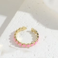Top view of a gold open ring with pink enamel hearts on a white textured background - Pink