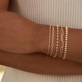 Fünfteiliges goldenes Büroklammer- und Perlenarmband-Set am Handgelenk eines Models - Gold (Feine Perle/Ovalglied/Perlenstrang/Großes Rechteckglied)