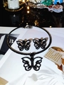Detailed view of gothic black butterfly necklace and stud earrings set on magazine - Black Butterfly Jewelry Set