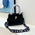Detail of black pebbled leather tote bag with gold logo and wide branded textile strap - Black