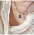 Detailopname van de elegante olijfgroene druppelhanger aan een zilveren slangenketting - Blauw Waterdruppel / Zilver