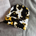 Detail of knit beanie texture with black, white and mustard yellow marble pattern - One Size / Black & Yellow Cow Print