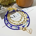 Detail view of multi-layered gold coffee bean chain with evil eye beads and pearls - Five-Layer Layered Stackable Set