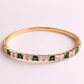 Detail of 18K gold-plated hinged bracelet with emerald-cut cubic zirconia in prong setting - White and Green Zirconia