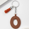 Close-up of a brown PU leather letter keychain with matching tassel and gold hardware - Brown Orange-Letter O
