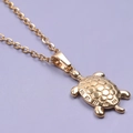 Detailed close-up of a 18k gold plated turtle pendant on a matching O-chain necklace - Necklace / Gold