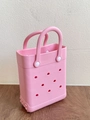 Detailaufnahme der pinken EVA-Strandtasche mit Lochmuster auf einer Holzoberfläche - Rosa