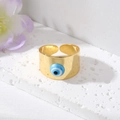 Detailopname van een vergulde Evil Eye ring op een stenen voet met bloemen - Hemelsblauwe Evil Eye