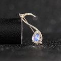 Macro shot of gold-plated deer brooch with crystal inlay and pear-cut blue gemstone - Music Note Brooch