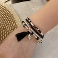 Detail of layered seed bead bracelets with black tassels and seashell charms on wrist - 6# Black-White Conch & Tassel Style