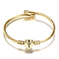 Detail van een 18K gouden kabelarmband met een gegraveerde hartbedel en de letter T - Letter T