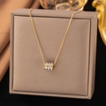 Elegant gold necklace with sparkling triple-ring crystal cylinder pendant on brown box - Cylinder Studded / Gold