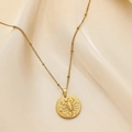 Detailed view of Scorpio zodiac gold pendant necklace on silky fabric background - Scorpio