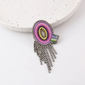 Close-up of colorful crystal brooch with shimmering tassel chains on a ceramic plate - Letter Q