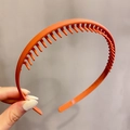 Matte orange non-slip headband with teeth design held against a grey background - Comb Style / 1# Comb-Dark Orange