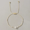 Primer plano de pulsera ajustable con cuentas crema y detalles metálicos dorados finos - Ojo de Gato Amarillo Pálido Trenzado
