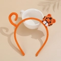 Detail of an orange knitted headband featuring a handmade tiger head and tail design - Tiger