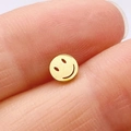Macro shot of a small gold smiley face earring on a finger showing realistic size - Gold Smiley Face