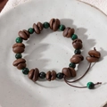 Macro view of handmade coffee bean bracelet with green malachite-style beads - Coffee Bean + Emerald Green Beads + Brown Cord