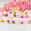 Close-up of pink plastic kids rings featuring cute acrylic bear, duck and fruit charms - Girls Transparent Style Rings