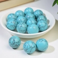 Polished round sky blue turquoise spheres with black webbed texture in a white bowl - Turquoise