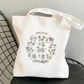 White canvas tote bag featuring Flowers for Bees illustration on a black chair - Save the Bees Theme