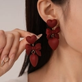 Vintage Ancora red heart and bow earrings with matte finish shown on female model - Matte Red Heart Bow Dangle Earrings (925 Sterling Silver Earring Post)