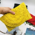 Close-up of a handmade corn husk woven clutch showing yellow textured straw details - Yellow